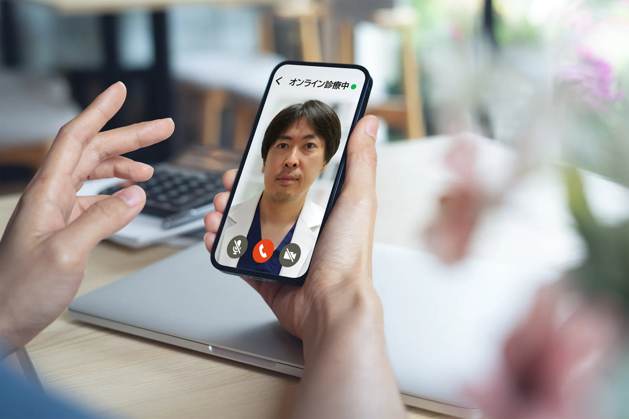 スマートフォンの画面でオンライン診療を行う近藤院長